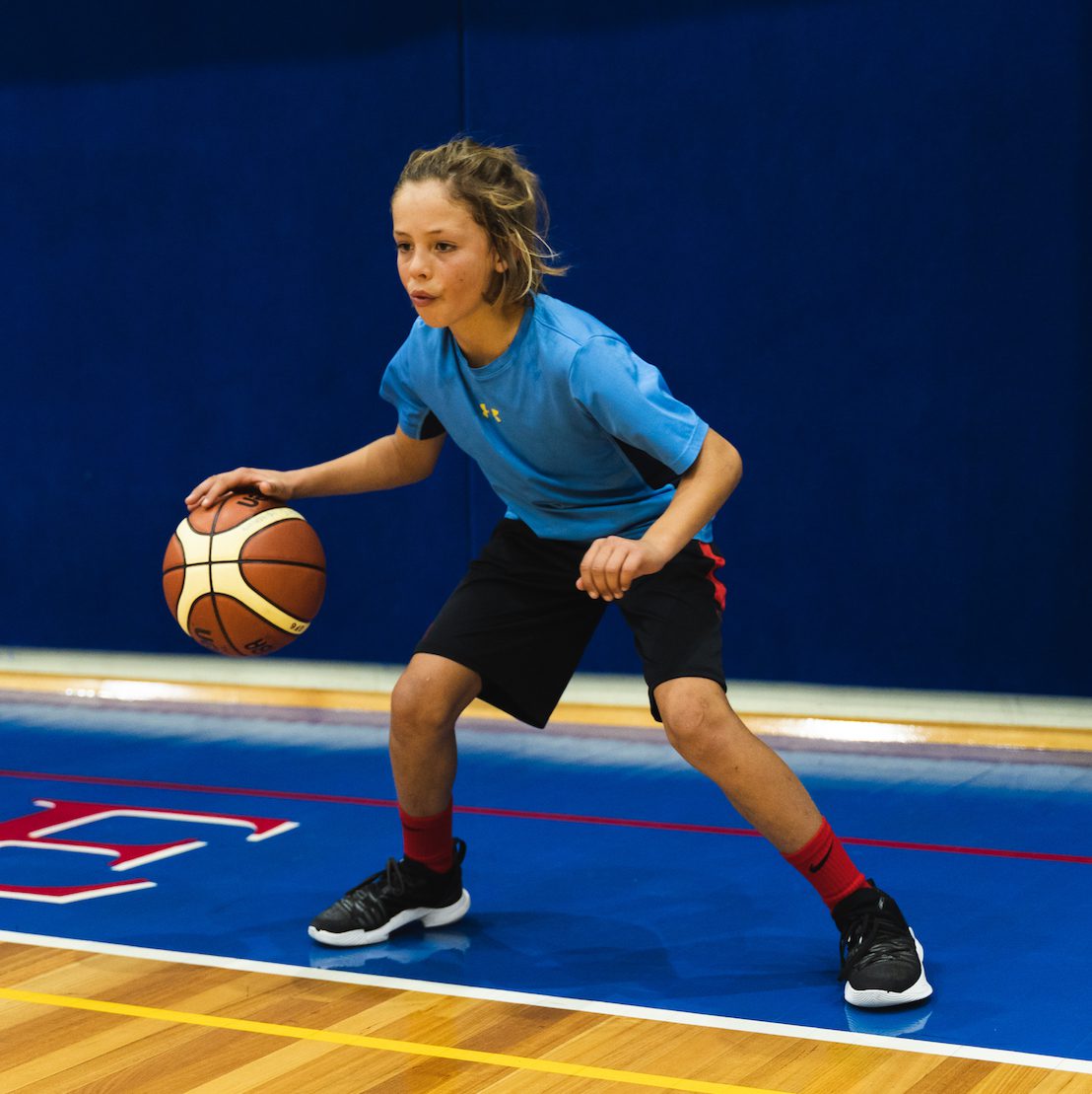 child dribbling basketball during one on one skills training