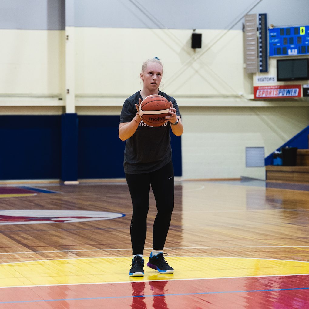 girl shooting basketball during basketball skills training